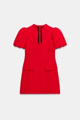 Vestido corto de color rojo con cuello redondo, escote en pico y mangas cortas abullonadas. Presenta cintura entallada, tapetas decorativas en la parte delantera y cierre de cremallera oculto en la espalda.