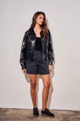 Campera bomber de cuero sintético negro, de corte oversize, con cuello solapa, cierre frontal metálico y bolsillos frontales con solapa.