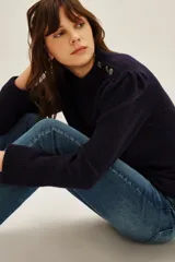 Sweater de punto color azul marino, con cuello alto y detalle de botones decorativos en el hombro. Presenta mangas largas con puños acanalados y un ligero fruncido en la parte superior de la manga.