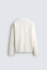 Camiseta de manga larga con corte relajado, confeccionada en tejido de algodón compacto. Presenta cuello redondo y detalle de costura en el centro de la espalda.