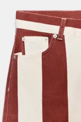Jeans de tiro alto con corte barrel y diseño de rayas verticales en color bordó y beige. Presenta cierre frontal con cremallera y botón, trabillas en la cintura y bolsillos funcionales en delantero y espalda.
