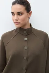 Chaqueta corta de tejido de punto color azul marino, con cuello mao abotonado y mangas tres cuartos. Presenta bolsillos frontales amplios.