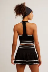 Conjunto deportivo compuesto por un top halter y una pollera pantalón de color blanco con líneas horizontales verdes.