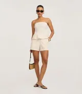 Short de tiro alto color beige confeccionado en algodón con lino, con trabillas en la cintura, cierre tradicional, bolsillos delanteros y costuras aparentes.