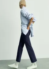 Jeans de tiro medio con diseño acampanado y corte cropped. Presenta bolsillos de parche en la parte delantera y trasera, cierre frontal con cremallera y botón, y trabillas para cinturón.
