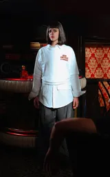 Remera blanca de manga larga superpuesta a una camisa blanca de manga larga, ambas con cuello. La prenda exterior tiene un estampado frontal en naranja con texto censurado inspirado en la película Pulp Fiction.