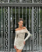 Vestido corto color chocolate con escote off-shoulder y mangas largas. Presenta frunces verticales en el frente.