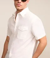 Camisa de corte comfort confeccionada en mezcla de lino y algodón, con cuello inglés, cierre frontal de botones, manga corta con dobladillo y un bolsillo frontal aplicado.