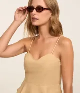 Blusa estilo corset color beige claro, con escote corazón y breteles finos. Presenta un corte ajustado en el torso y un volado peplum en el bajo.