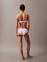 Bombacha tipo hipster de la línea invisible de Calvin Klein, confeccionada en microfibra ligera con bordes cortados a láser sin costuras. Presenta un diseño de talle bajo con cobertura total en la parte trasera y el logo de la marca estampado en la cadera.