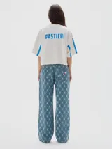 Remera cropped de algodón con efecto lavado, cuello redondo y mangas cortas con franjas laterales verticales. Presenta estampa frontal con texto y diseño gráfico.