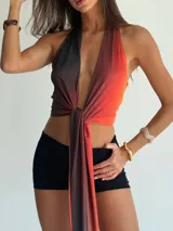 Top halter de tela brillante con efecto degradado que va del negro al naranja rojizo, anudado al frente.
