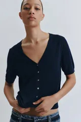 Chaqueta de punto azul marino confeccionada en lana extrafina, con cuello en V, manga corta y cierre frontal con botones.