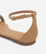 Sandalia plana color nude con tira fina con aplicación de strass y mini espejos, cierre en el tobillo, puntera redonda y taco bajo plano.