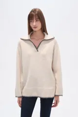 Sweater negro holgado con cuello en V y ribete en color crema en cuello, puños y ruedo.