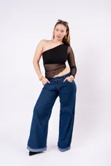 Remera negra de diseño asimétrico con un solo hombro. Presenta un cuerpo con panel de malla transparente en la cintura y una manga larga de tul transparente. El corte es ajustado y el dobladillo inferior tiene una forma irregular.