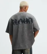 Remera oversized masculina de media malla con toque gamuza, color gris oscuro con efecto lavado. Presenta un bordado blanco en forma de media luna en el pecho y un estampado lettering en la parte delantera y trasera.