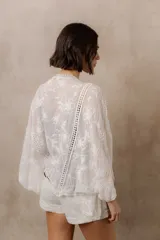 Kimono marfil de silueta amplia, confeccionado en tela con bordados florales y detalles calados. Cuenta con mangas amplias tres cuartos, frente abierto y terminaciones decorativas.