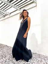 Vestido largo de corte holgado en color negro, con escote en V profundo decorado con lentejuelas negras brillantes. Presenta un diseño sin mangas y una caída fluida.