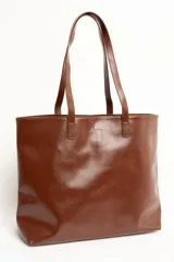 Bolso tipo tote bag color marrón, confeccionado en cuero sintético, con doble asa superior y detalle de placa metálica dorada con logo en la parte frontal.