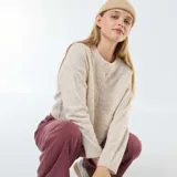 Chaqueta color beige de tejido de punto, corte cropped, con cuello redondo y cierre frontal con botones.