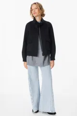 Chaqueta corta de paño color gris, con cuello alto, cierre frontal con cremallera y bolsillos delanteros con solapa.