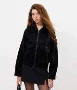Campera bomber de poliuretano texturizado en color negro, con cuello camisero, cierre frontal, bolsillos aplicados en el pecho y ruedo elástico.