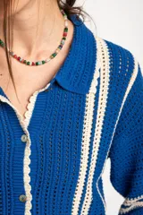 Cardigan oversize de crochet de algodón peinado, color azul con rayas verticales blancas, cuello tipo polo y cierre frontal de botones.