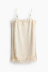Vestido corto de satén color beige con breteles spaghetti ajustables, escote recto y detalles de encaje en el escote y el bajo.