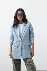 Blazer de jean color celeste con silueta recta y corte sastrero. Presenta solapas clásicas, cierre frontal con botón forrado, bolsillos con tapa y detalle de botones forrados en los puños.