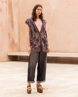 Chaleco oversize de punto con hilo lúrex, cuello en V y cierre frontal de botones. Presenta un estampado jacquard con efecto marmolado en tonos marrones y morados, bolsillos frontales aplicados y ribetes en contraste en el escote, sisas y dobladillo.