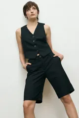 Bermuda sastrera negra de corte recto con bolsillos laterales y cierre frontal con botón y cremallera.