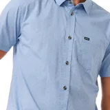 Camisa celeste con microestampado, de manga corta, con bolsillo en el pecho y cierre con botones.