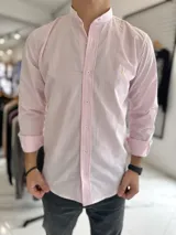 Camisa de manga larga con cuello mao, de diseño a rayas verticales en tonos rosado y blanco. Cuenta con cierre frontal de botones y bordado pequeño en el pecho.