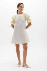 Vestido corto a rayas verticales color gris y blanco, con cuello redondo y mangas cortas abullonadas color amarillo pálido con detalle de elástico en el puño.