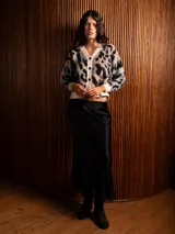 Saco tipo cárdigan de tejido suave y peludo, con estampado animal print en tonos beige, negro y marrón. Presenta cuello en V, cierre frontal con botones y mangas en contraste de color con diseño animal print.