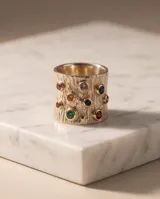 Anillo ancho de plata 925 con lámina de oro de 18k en los bordes, con textura estriada y engastes de circonias de colores.