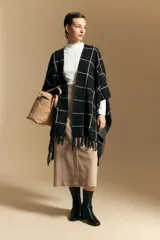Poncho abierto de tejido de punto con diseño de cuadros grandes en contraste. Presenta un patrón reversible en tonos negro y marrón, con un estilo envolvente y versátil.