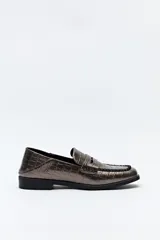 Mocasín de cuero sintético con textura de reptil en color gris metalizado, con punta cuadrada y detalle de costura reforzada en la capellada.