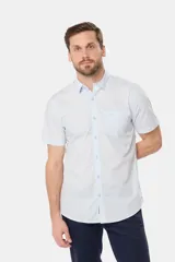 Camisa lisa de manga corta color crema, confeccionada en 100% algodón, con cuello abotonado y un bolsillo en el pecho.