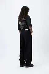 Pantalón jean negro de corte amplio y estilo carpenter, con tiro medio, bolsillos utilitarios y presillas laterales.