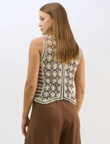 Chaleco de tejido crochet con diseño calado de motivos florales y geométricos. Presenta escote en V, cierre frontal con botones y detalles de vivos a contraste en color negro en sisas, escote y ruedo.