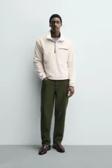 Sudadera de tejido polar con textura efecto pelo, corte relajado, cuello subido con cierre frontal de cremallera, manga larga con puños elásticos y bolsillo con cierre en el pecho.