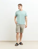 Remera tipo henley de manga corta, color beige, con cuello redondo y cartera de botones frontal.
