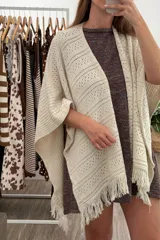 Ruana tejida color arena, con diseño calado de rombos y flecos en el borde inferior.