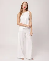 Pantalón palazo blanco de lino, tiro alto, con elástico en la cintura trasera, cierre delantero, bolsillos laterales y tajos a los costados.