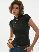 Top de encaje floral negro, al cuerpo, con cuello alto estilo mandarín y broches decorativos dorados en el frente.