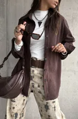 Sobrecamisa de pana color chocolate, con corte holgado, cuello clásico y cierre frontal de botones. Presenta mangas largas con puños abotonados y textura acanalada.
