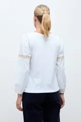 Remera de estilo boho color blanco, con mangas largas, escote en V con cordones y detalle de bordado en el pecho.