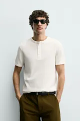 Camiseta de manga corta con cuello panadero y cierre frontal de tres botones. Presenta una textura acanalada y un corte regular fit.